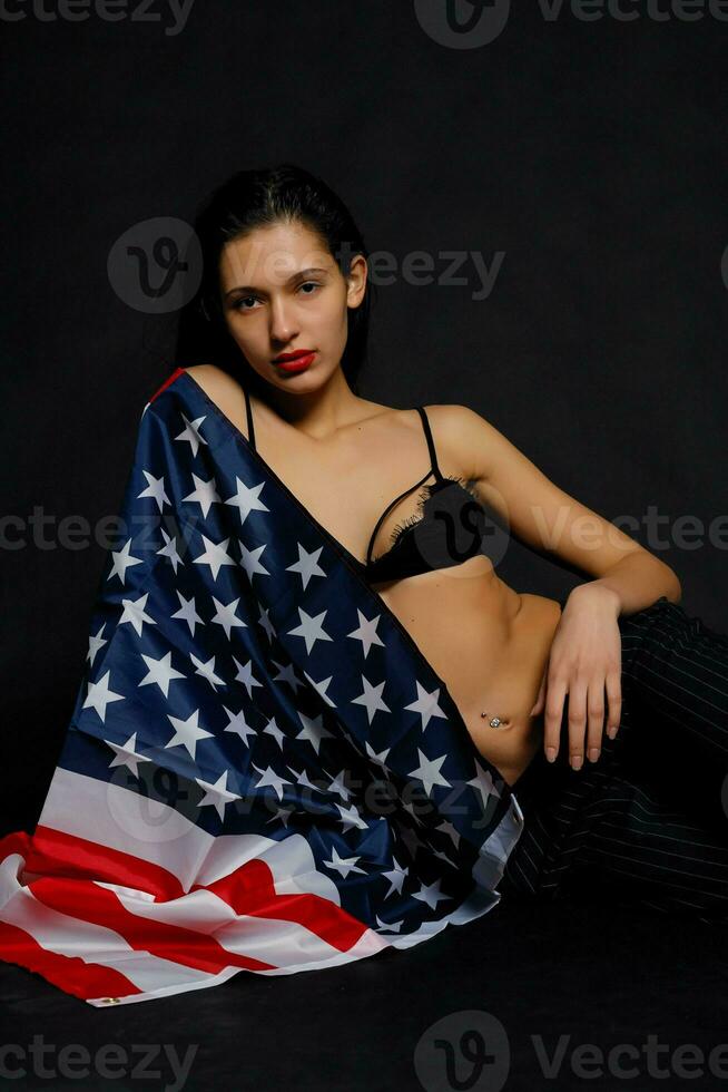 ritratto femmina atleta avvolto nel americano bandiera contro nero sfondo foto