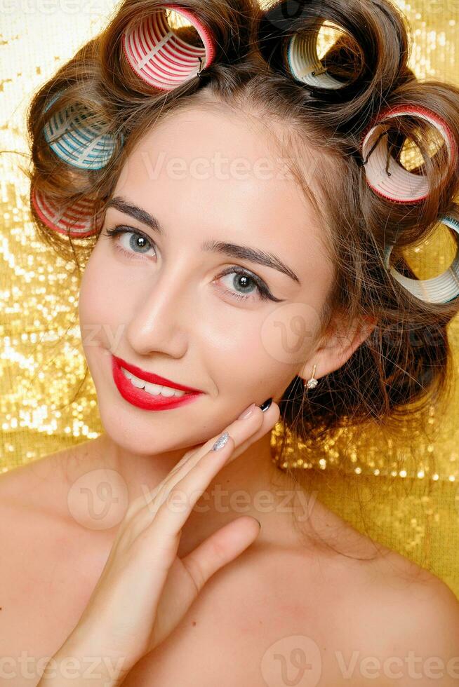 bellissimo ragazza nel capelli bigodini isolato su oro foto