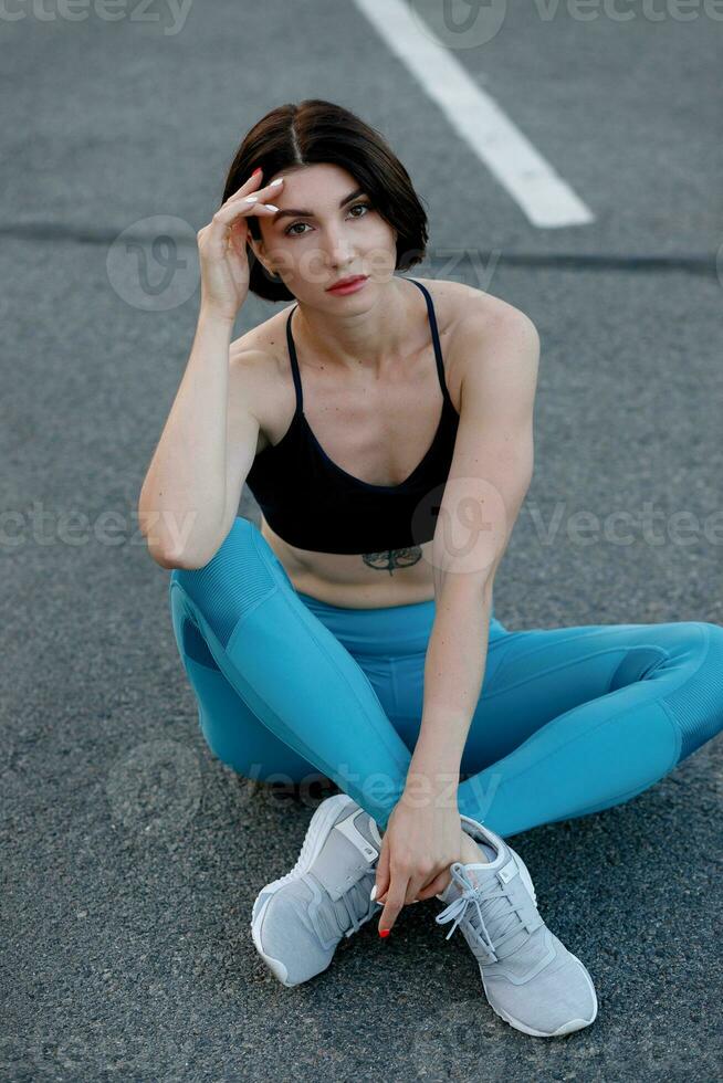 in forma giovane donna seduta all'aperto dopo allenarsi sessione nel mattina. foto