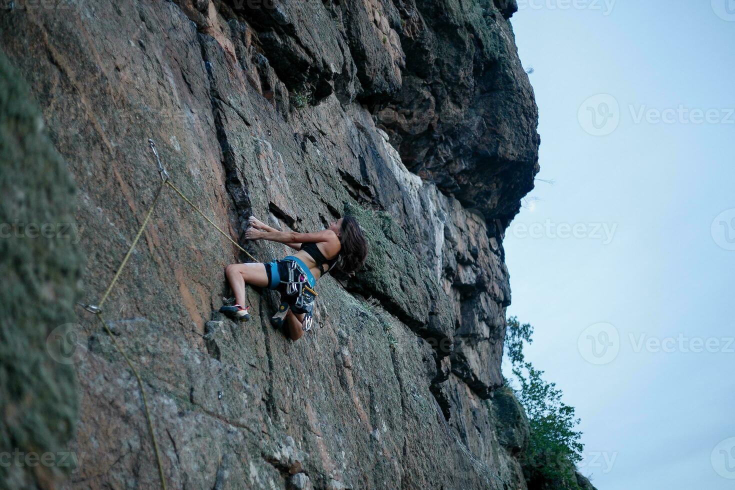 un' ragazza si arrampica un' roccia. donna impegnato nel estremo sport. foto