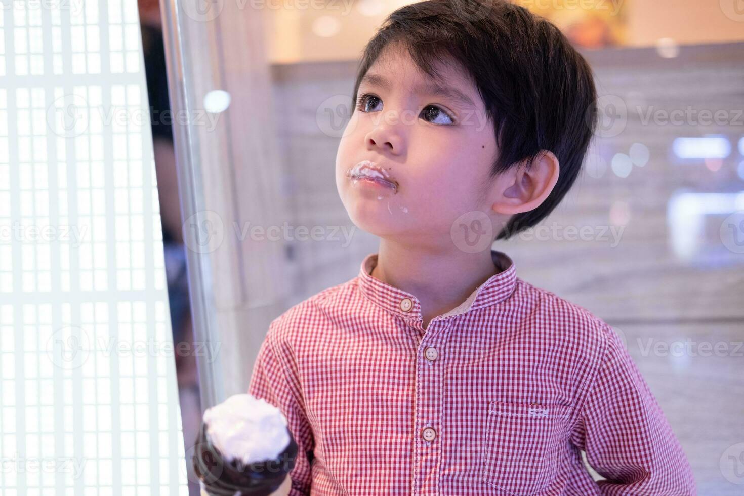 poco asiatico ragazzo mangiare delizioso cioccolato ghiaccio crema foto