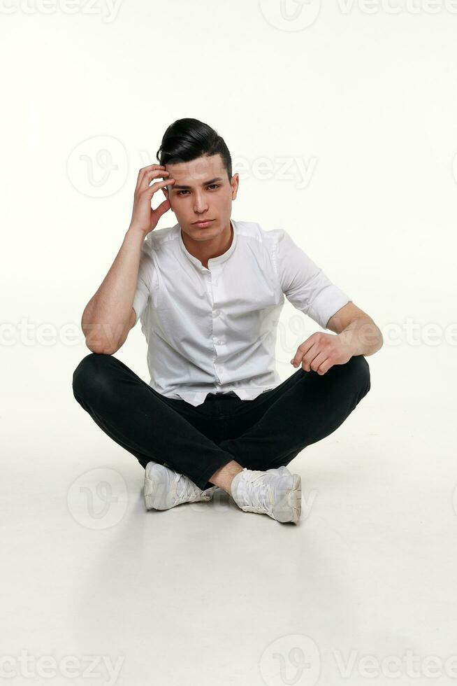 bello, giovane, di moda uomo è seduta su il pavimento nel studio foto