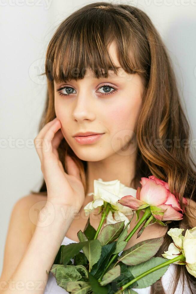 poco bella ragazza nel rosa detiene il mazzo di Rose. foto