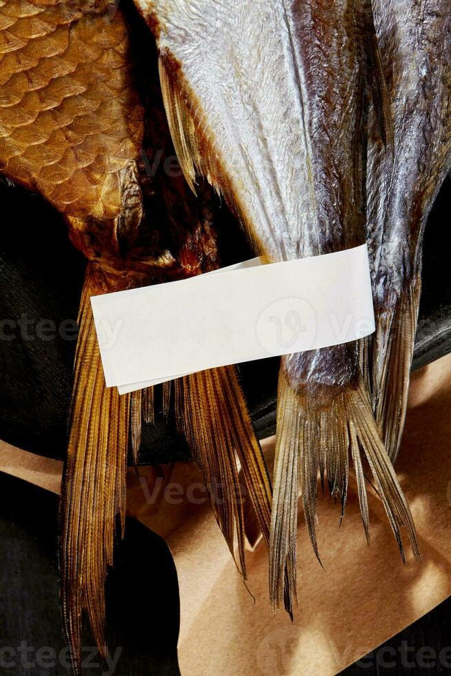 code su affumicato e asciugato ad aria salato pesce con etichetta su nero fondale con kraft carta foto