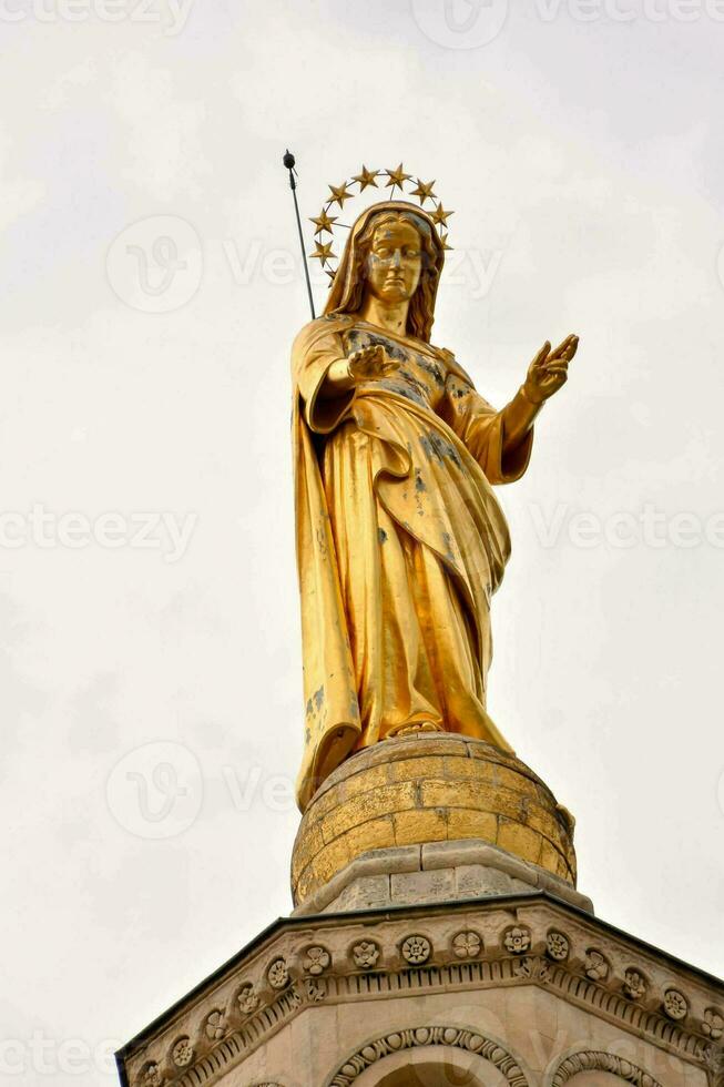 un' oro statua di il vergine Maria su superiore di un' edificio foto