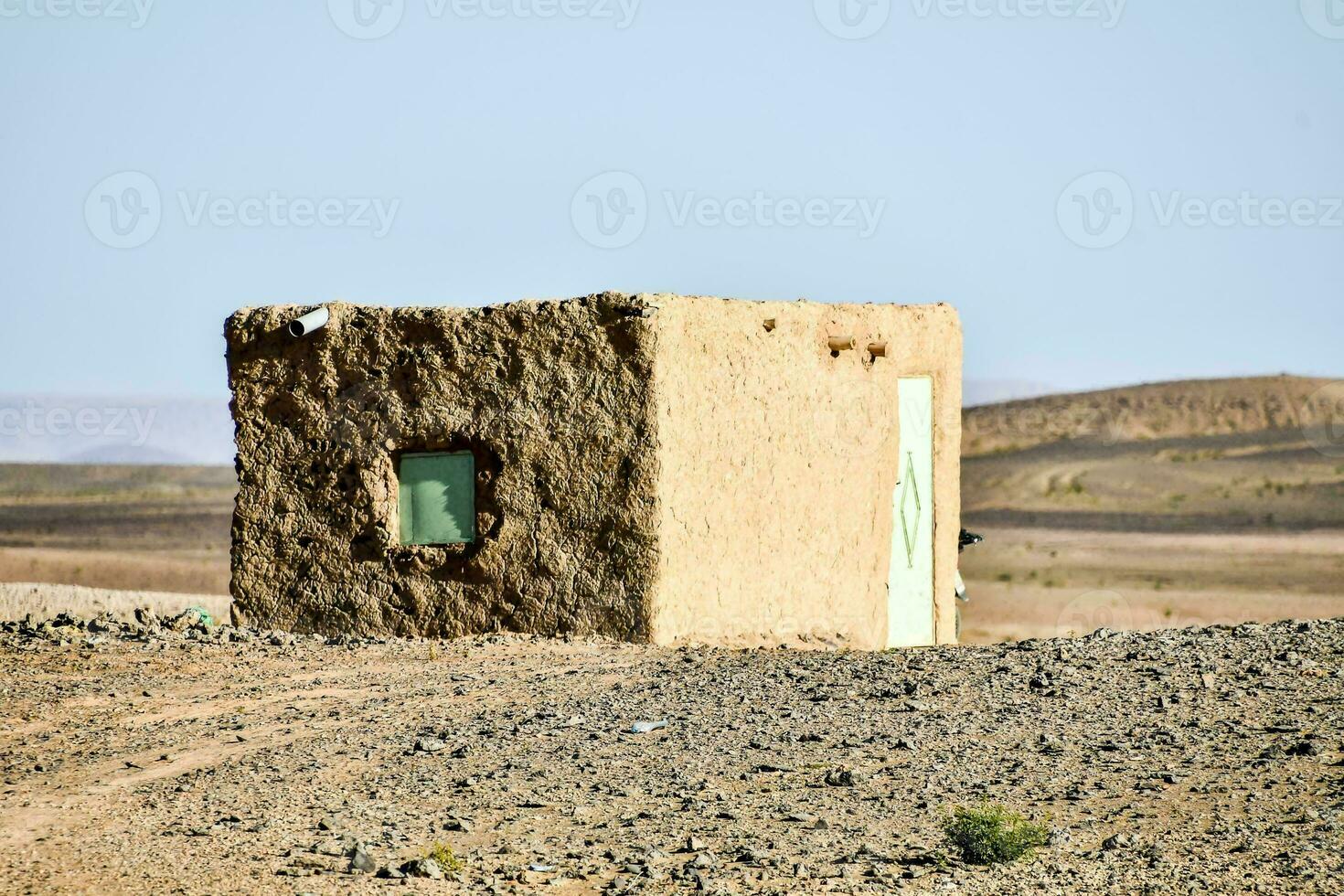 un' piccolo Casa nel il deserto con un' verde finestra foto