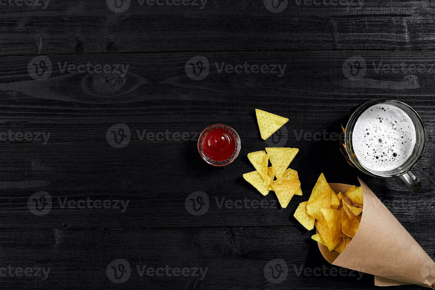 superiore Visualizza di tortilla patatine fritte con salsa, bicchiere di birra su nero di legno sfondo foto