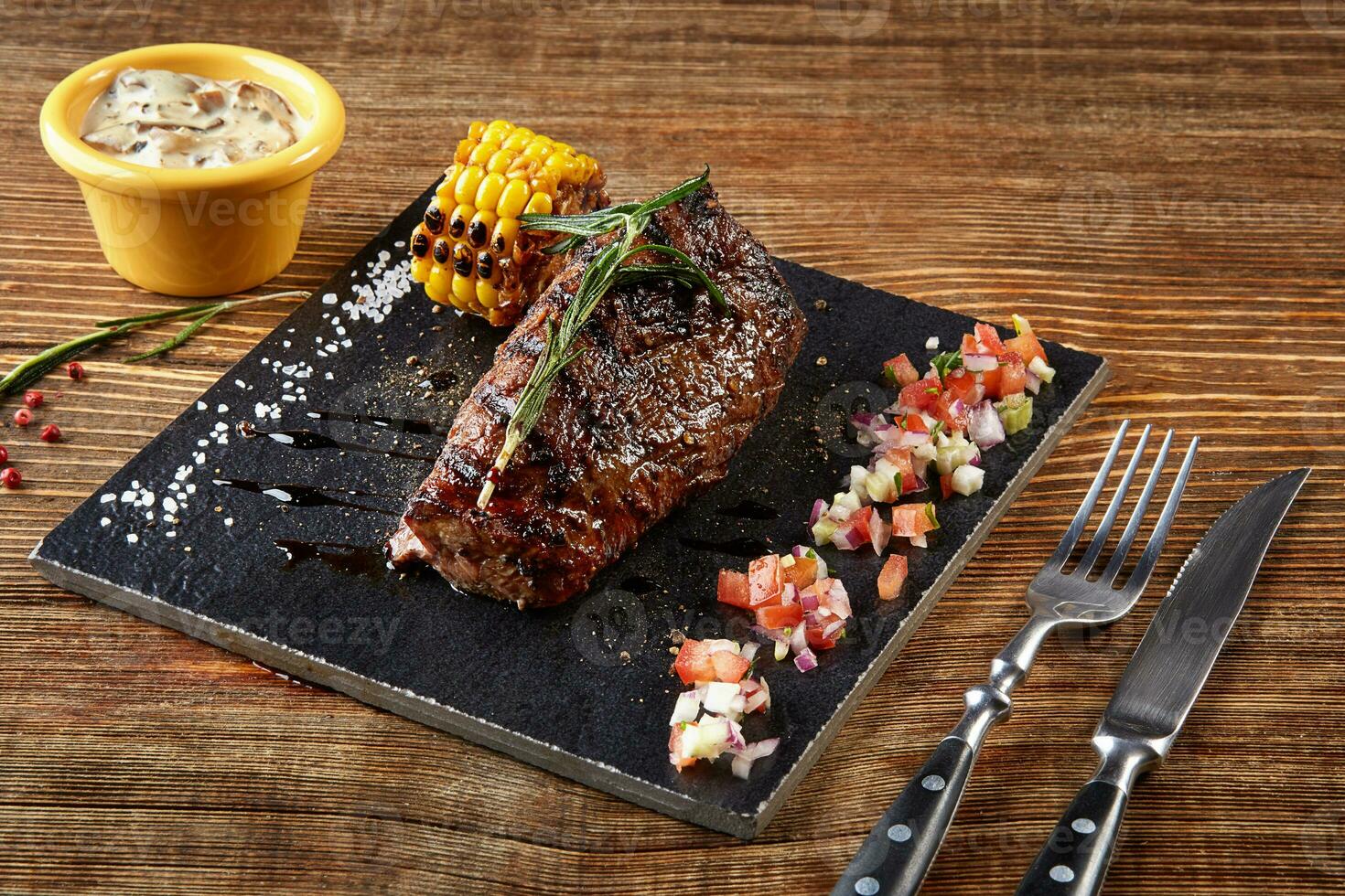 bistecca di manzo con grigliato Mais su nero tavola e funghi salsa su di legno tavolo foto