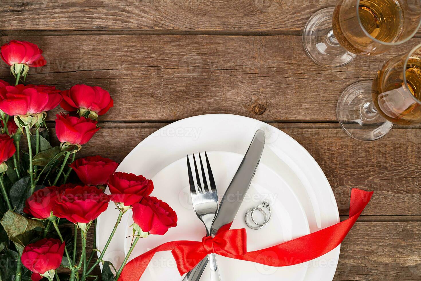 San Valentino giorno cena tavolo ambientazione con rosso nastro, Rose, coltello e forchetta squillare al di sopra di quercia sfondo. foto