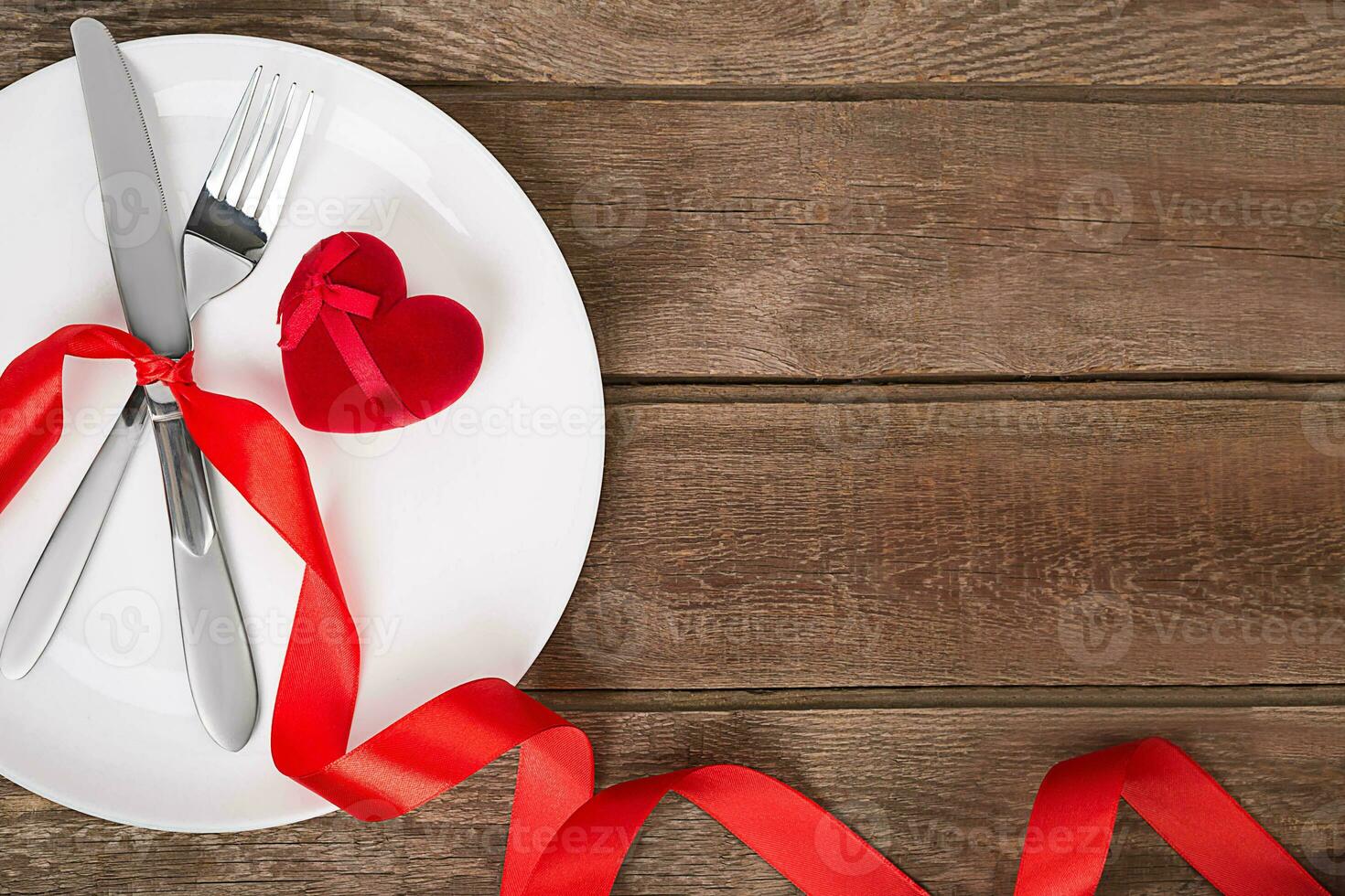 san valentino giorno tavolo ambientazione con piatto, forchetta, coltello, rosso cuore e nastro. sfondo foto