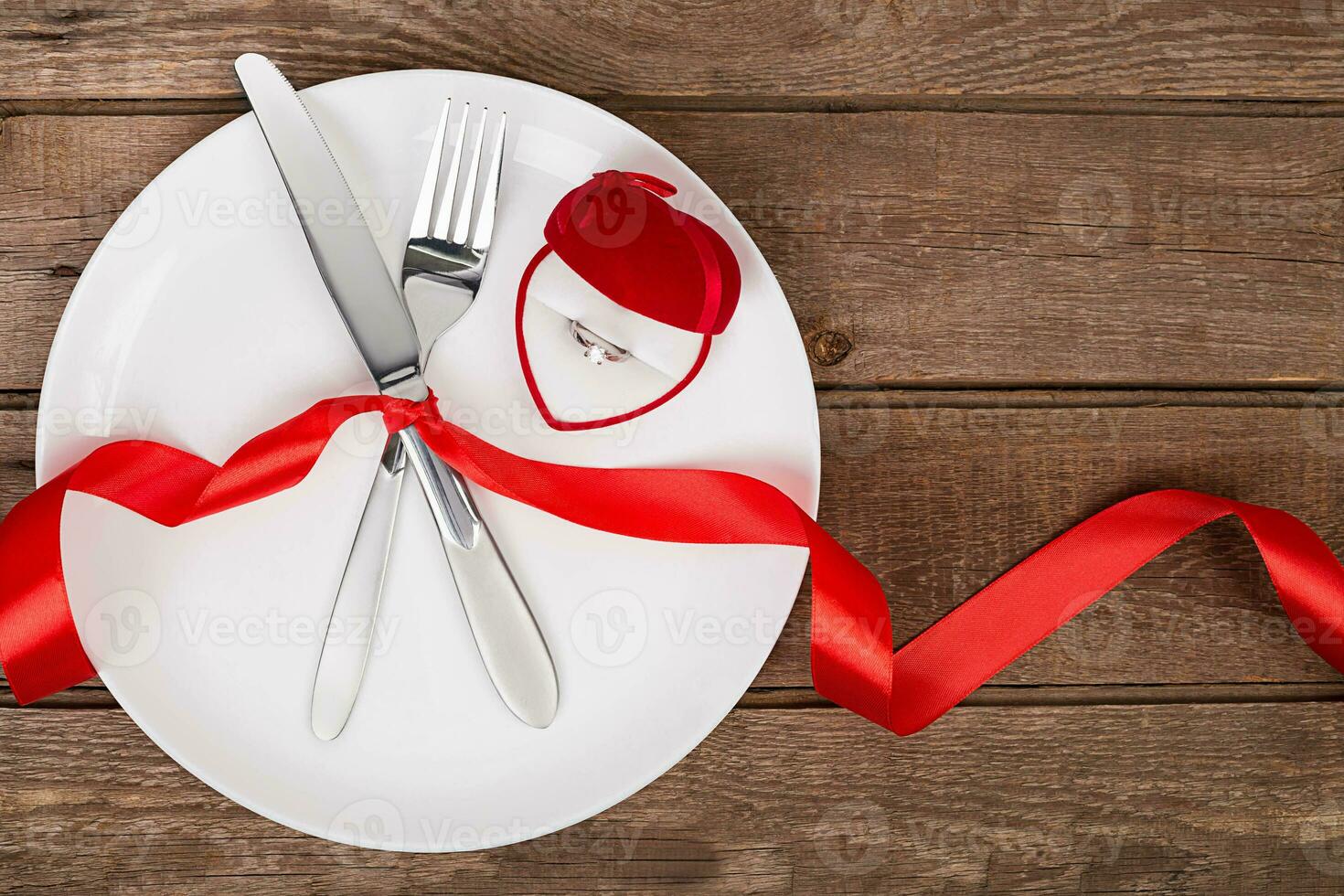 san valentino giorno tavolo ambientazione con piatto, forchetta, coltello, rosso cuore, squillare e nastro. sfondo foto