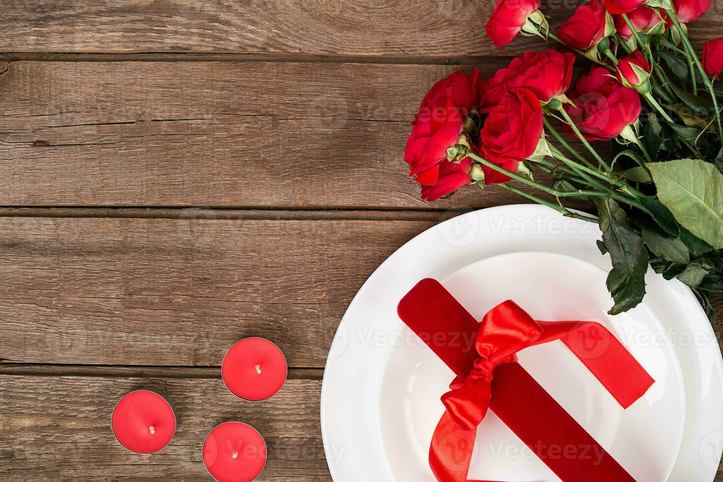 superiore Visualizza avvicinamento di romantico cena servendo con un' mazzo rosso Rose e presente sopra il bianca piatto foto
