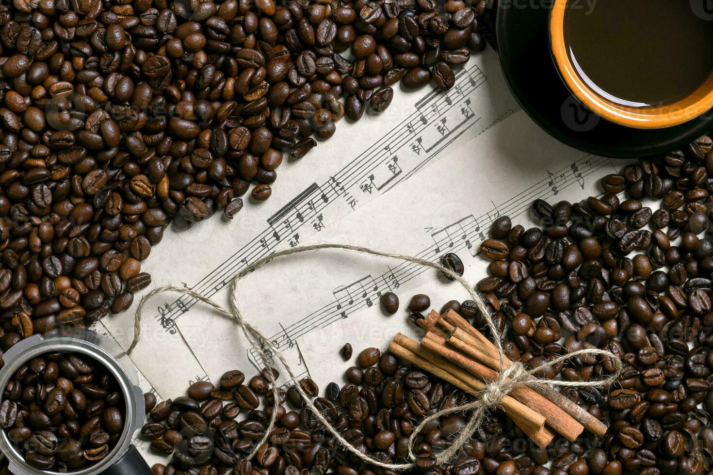 caffè fagioli, cannella bastoni e tazza di fermentato caffè su foglio musica sfondo, Visualizza a partire dal sopra con spazio per testo foto