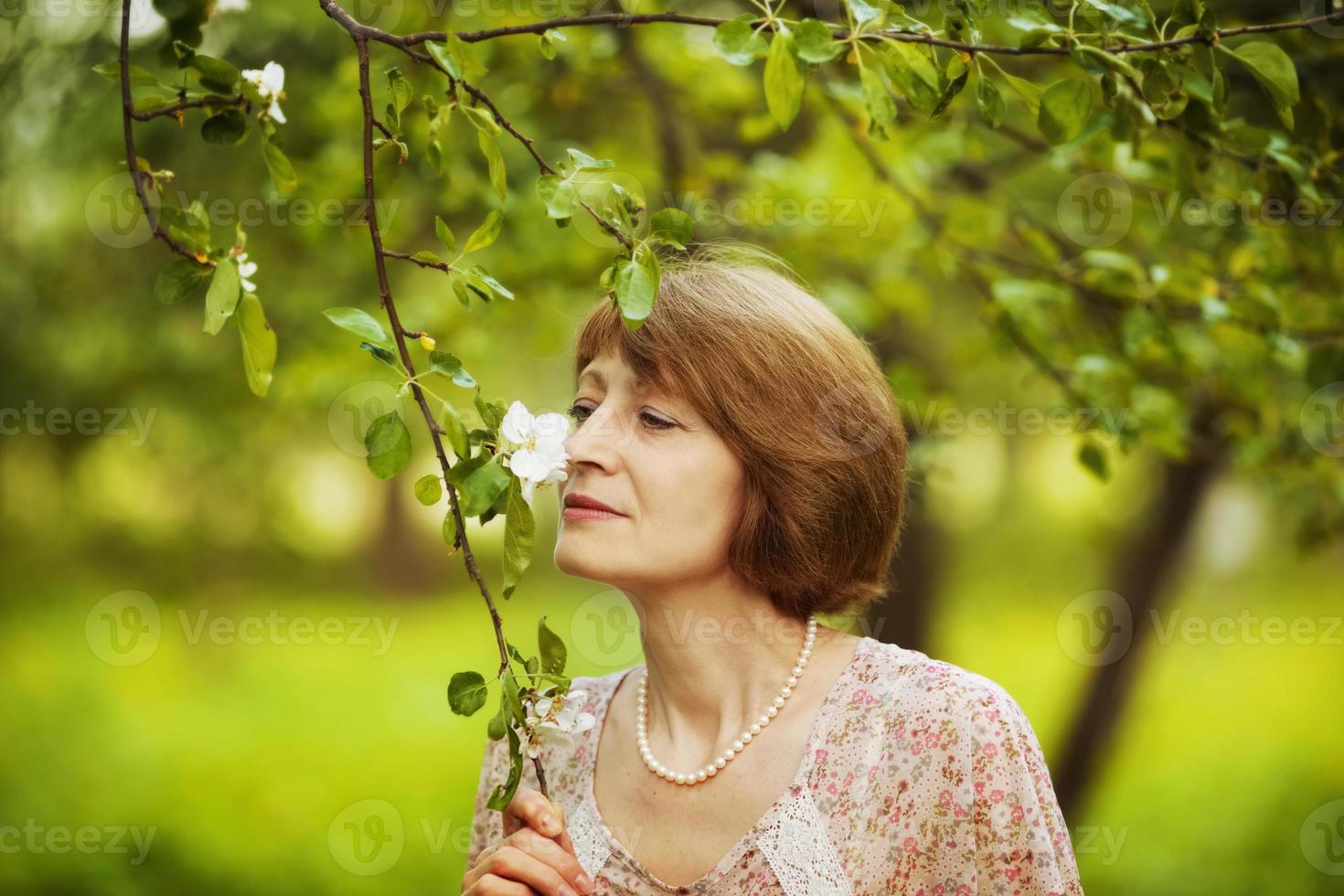 la donna felice inala l'aroma di un fiore foto