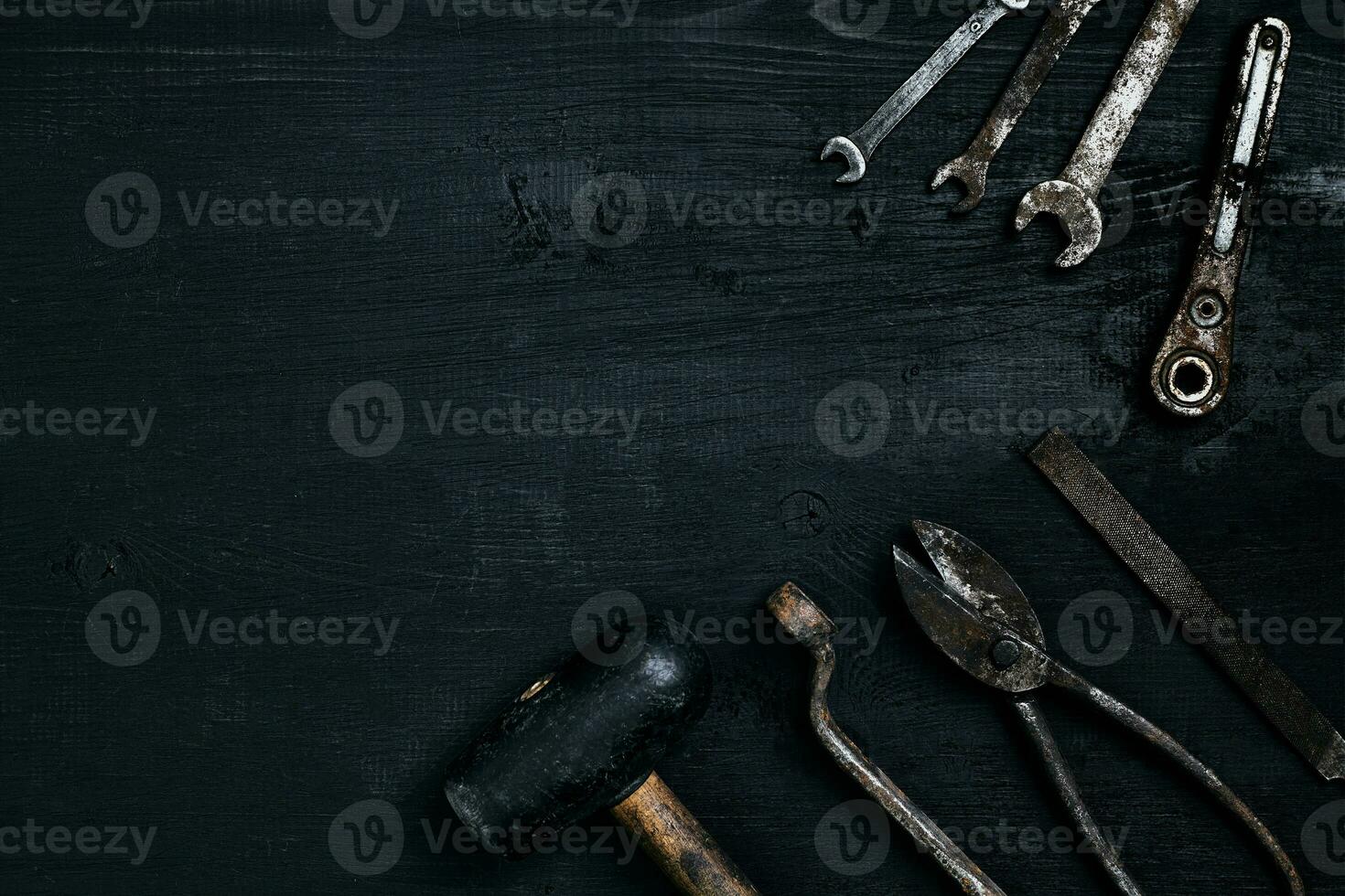 vecchio, arrugginito utensili dire bugie su un' nero di legno tavolo. martello, scalpello, metallo forbici, chiave inglese. foto