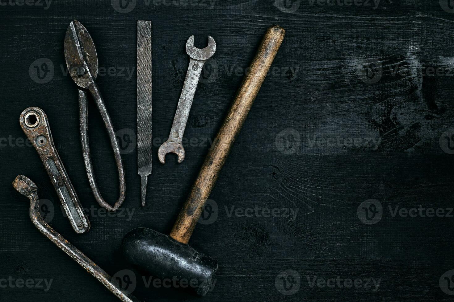 vecchio, arrugginito utensili dire bugie su un' nero di legno tavolo. martello, scalpello, metallo forbici, chiave inglese. foto