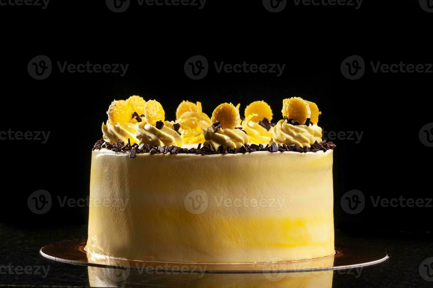 il giro giallo compleanno torta. decorativo crema decorazioni su il torta. nero sfondo. foto