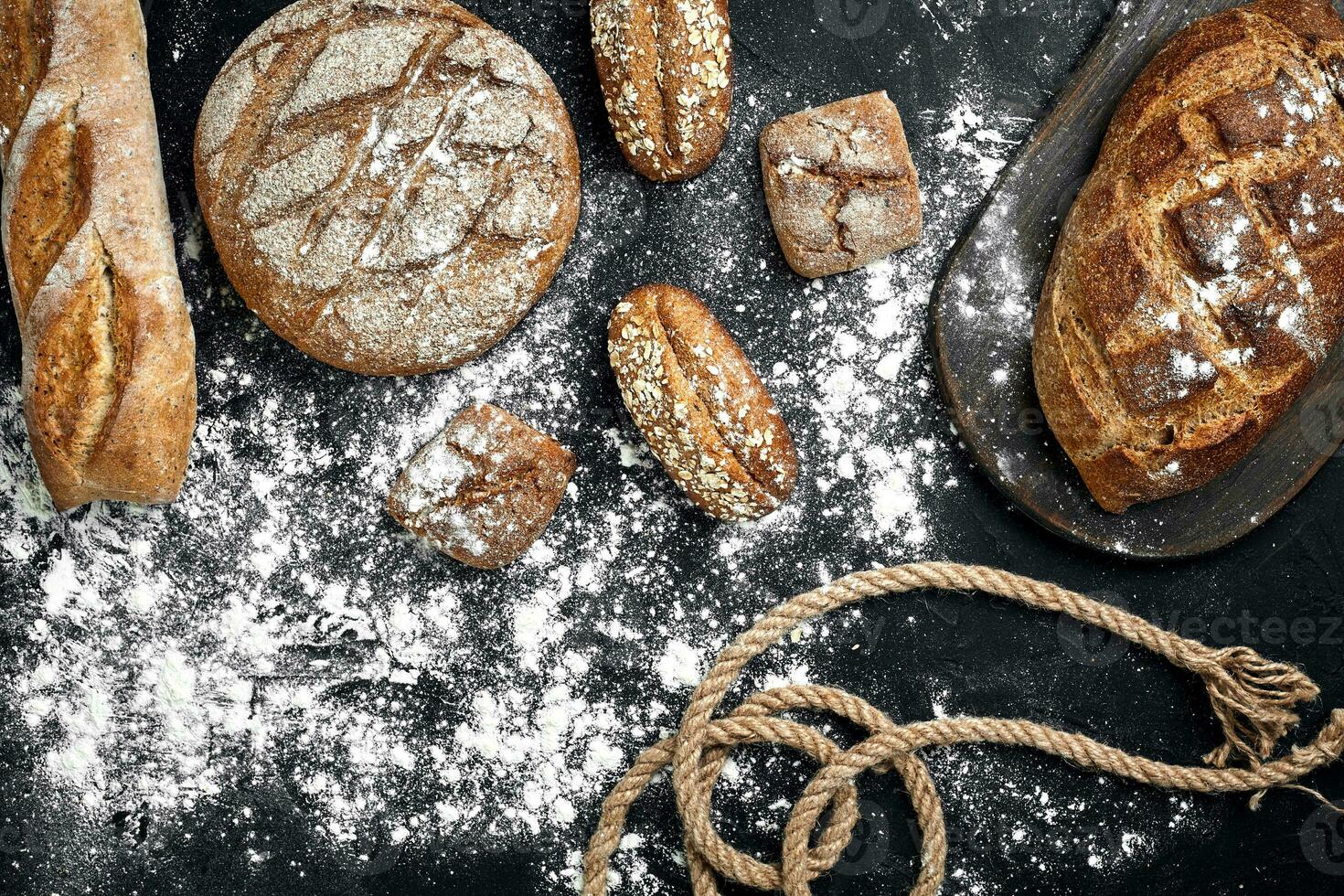 fatti in casa segale pane cosparso con Farina e vario cereali e semi su un' nero sfondo con spighette di Grano o segale e avena. foto