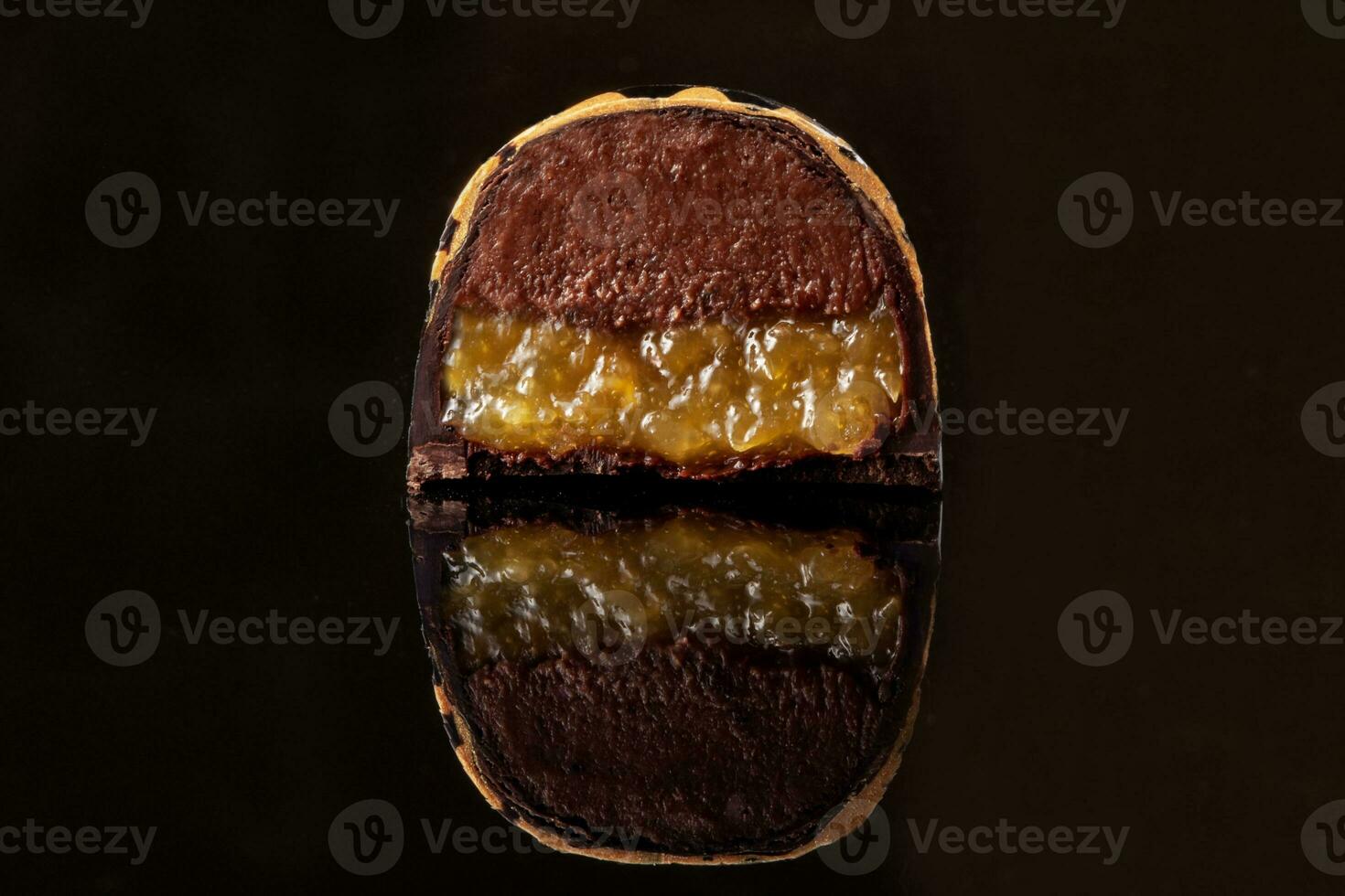 tagliare lusso fatto a mano caramella con cioccolato e giallo confiture Riempimento su nero sfondo. foto
