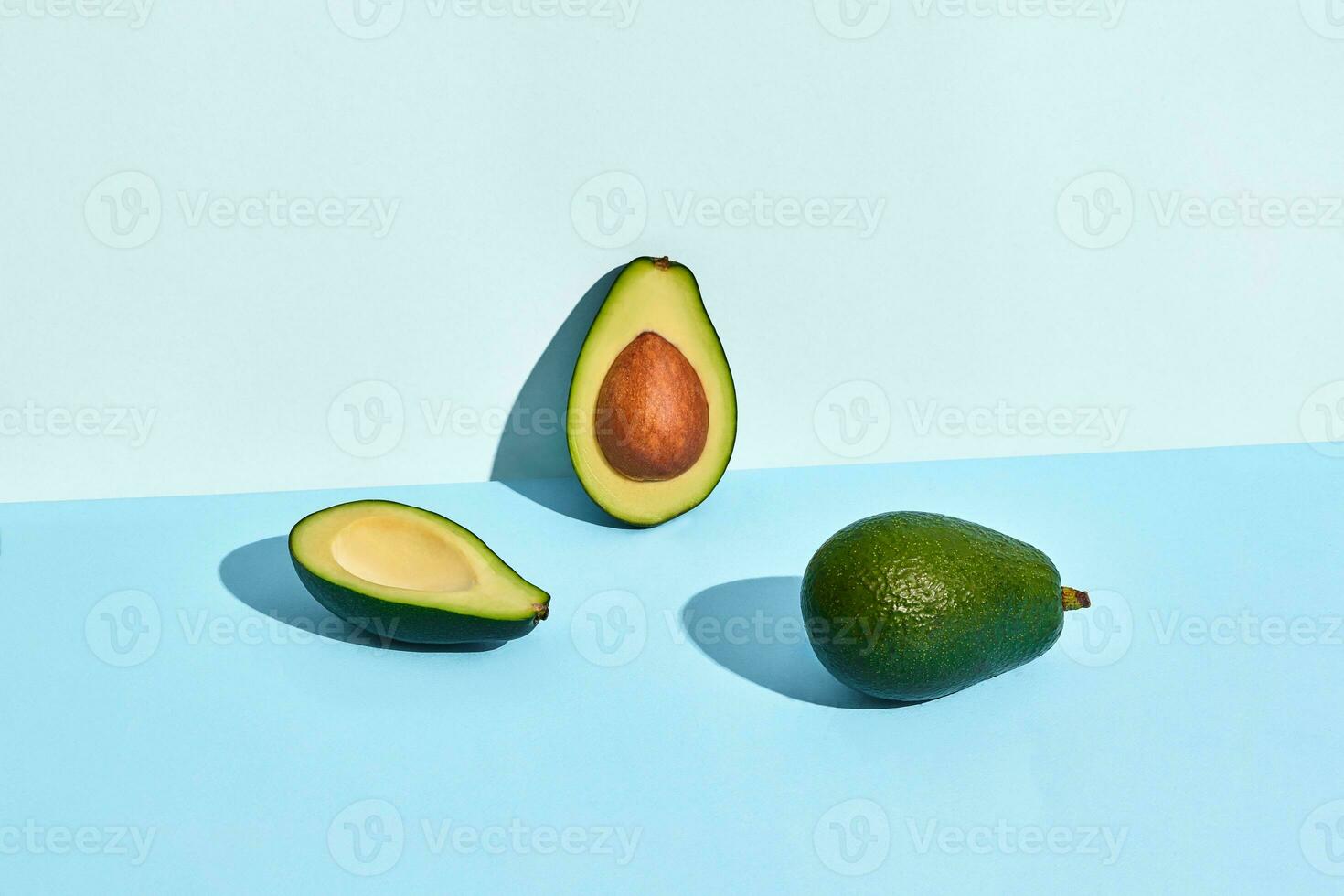 tre metà di avocado frutta su blu sfondo foto