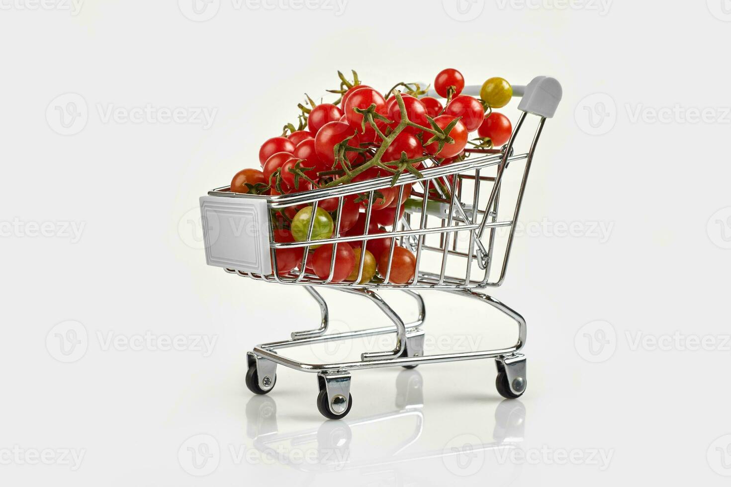 mini shopping carrello pieno con ciliegia pomodori su bianca sfondo foto