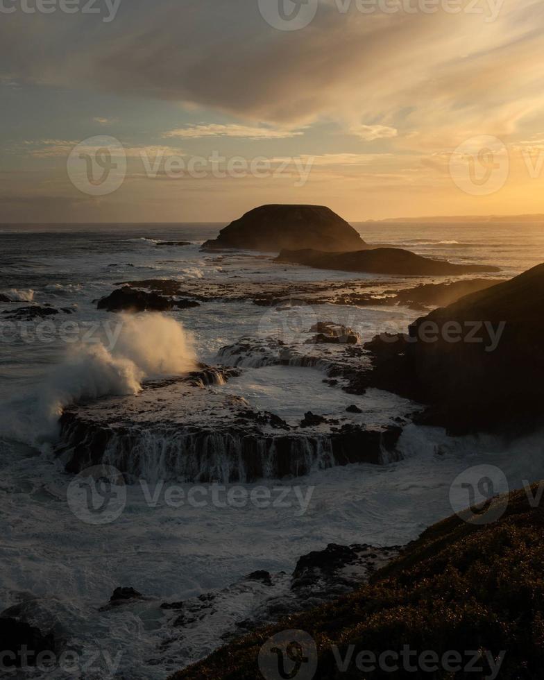 l'acqua nel mare agitato si è schiantata contro le scogliere in australia al tramonto foto