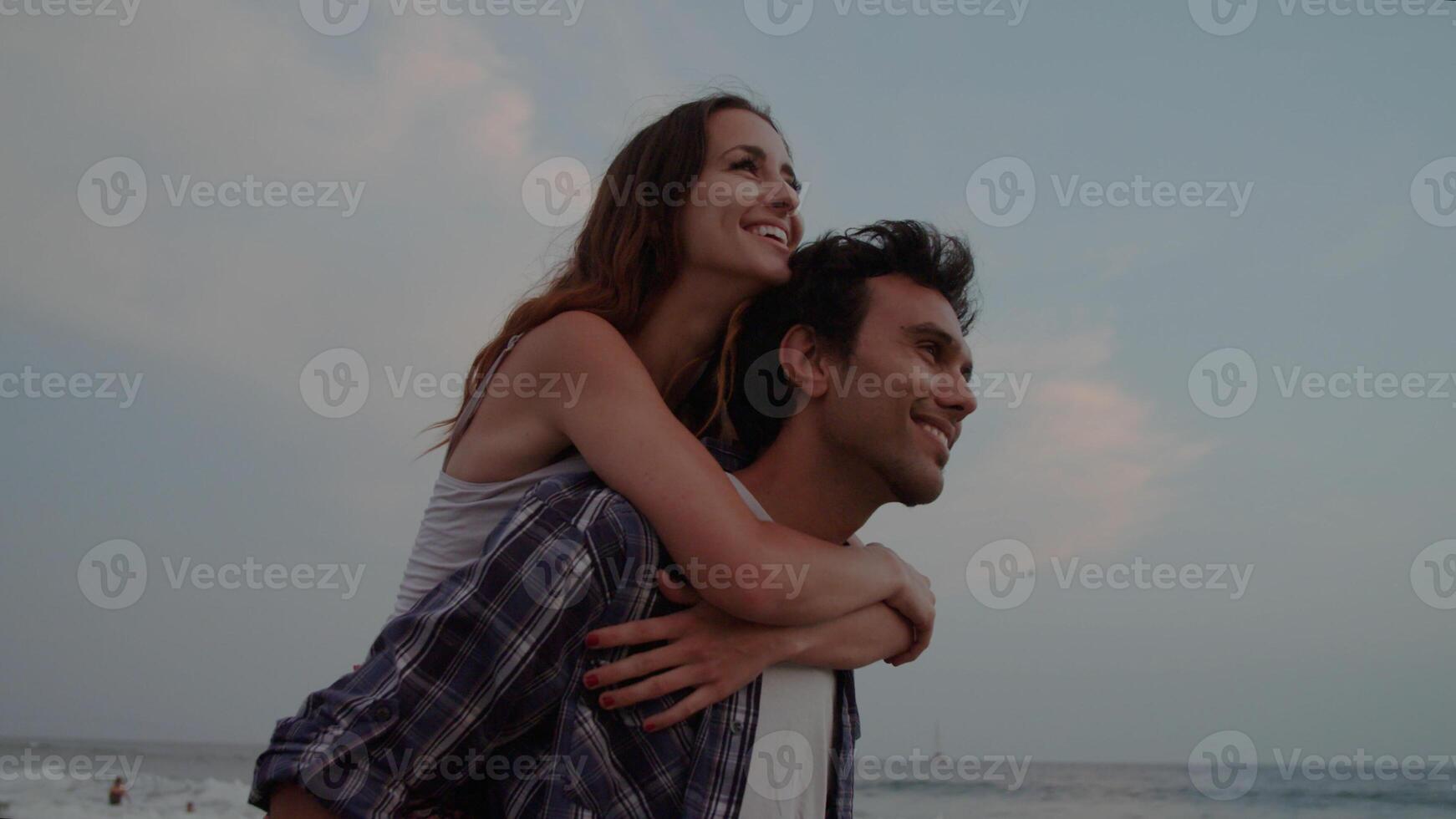 rallentatore di giovane che dà donna piggy back sulla spiaggia foto