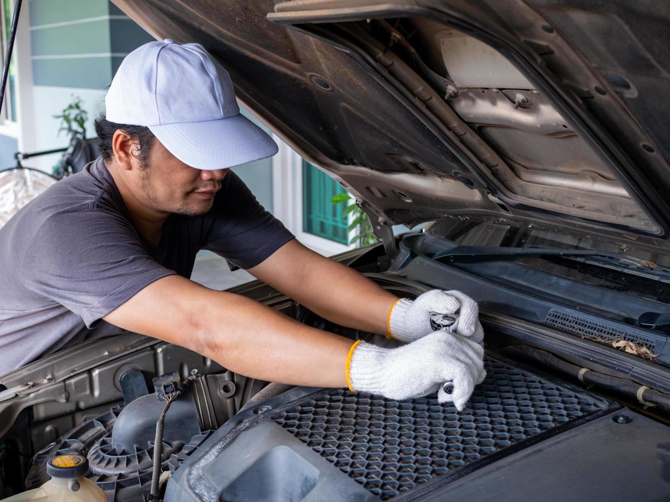 meccanico che tiene in mano una chiave inglese durante la riparazione di un'auto. foto