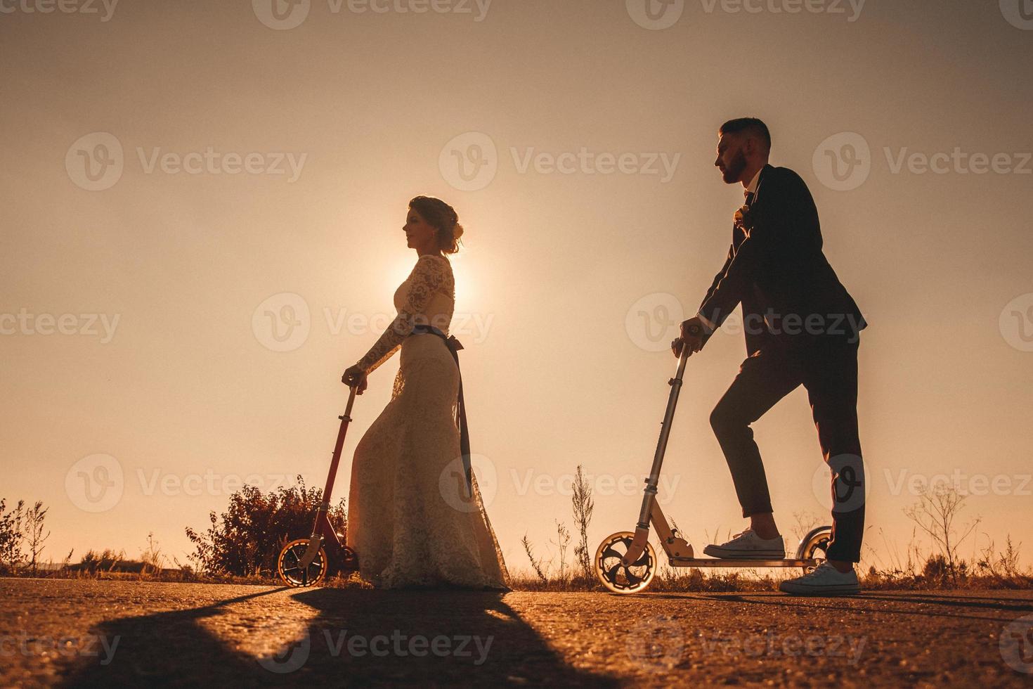 silhouette sposi in sella a uno scooter lungo la strada al tramonto foto