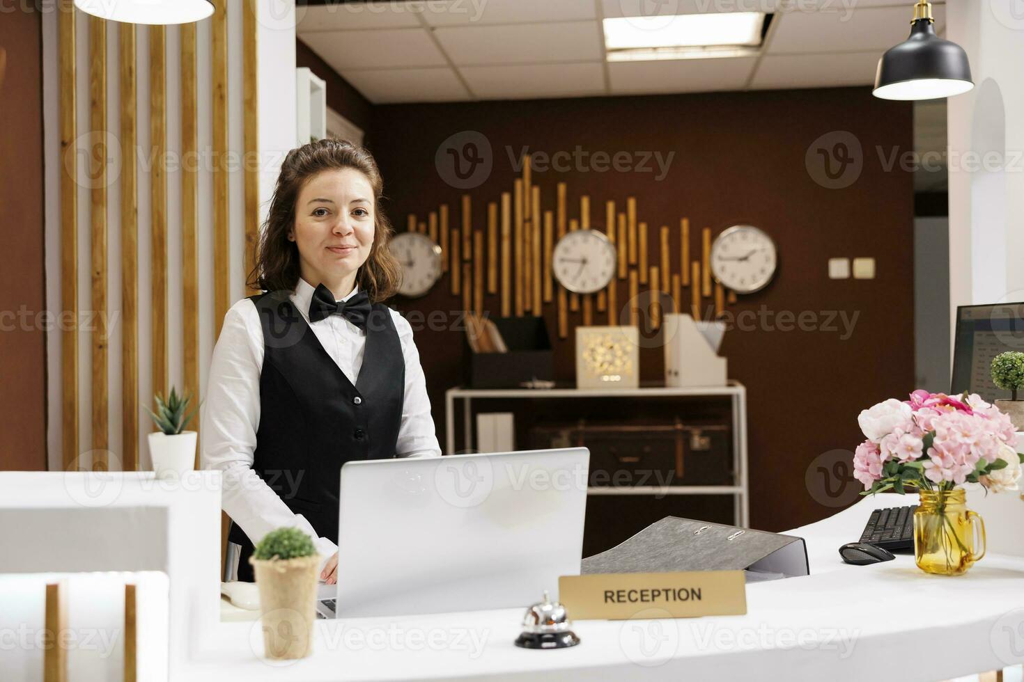 amichevole addetto alla reception a davanti scrivania preparato per salutare ospiti nel Hotel atrio, fornire eccellente cliente Servizi per garantire piacevole restare. concierge Lavorando a ricezione, benvenuto le persone. foto