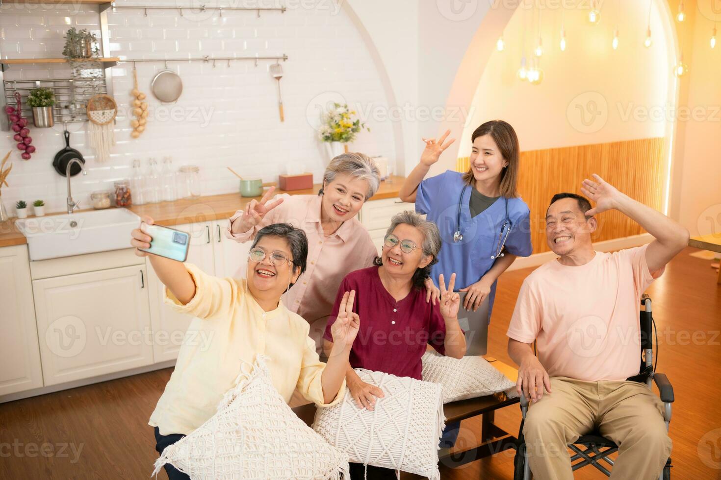 gruppo di asiatico anziano e badante avendo divertimento con autoscatto nel il assistenza infermieristica casa. foto