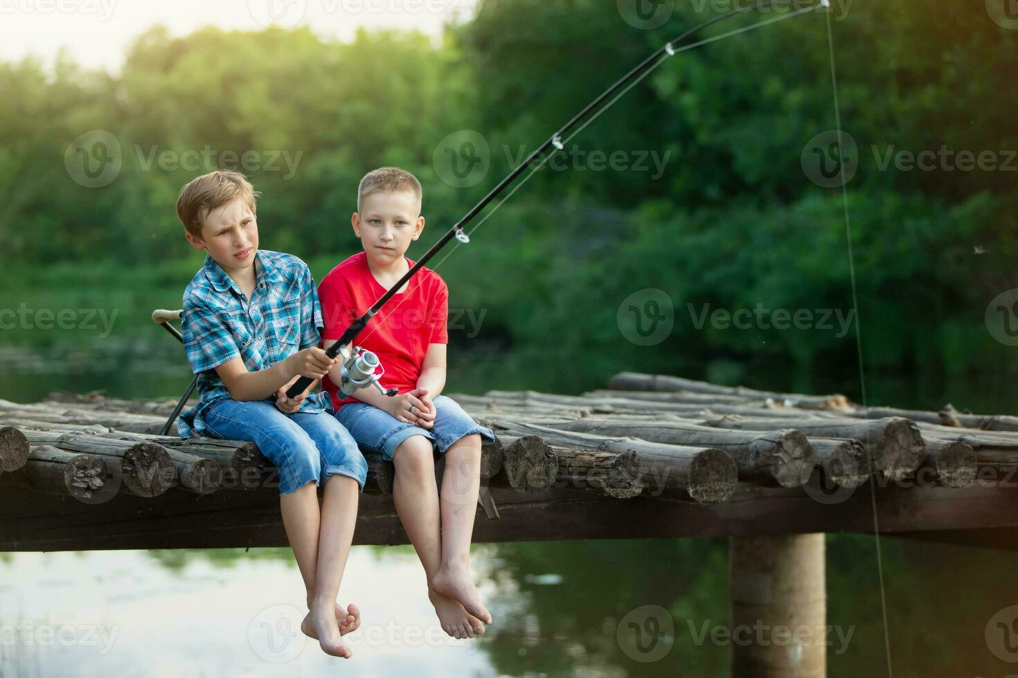 il ragazzi sedersi su un' di legno ponte e pesce. bambini su un' pesca viaggio. foto