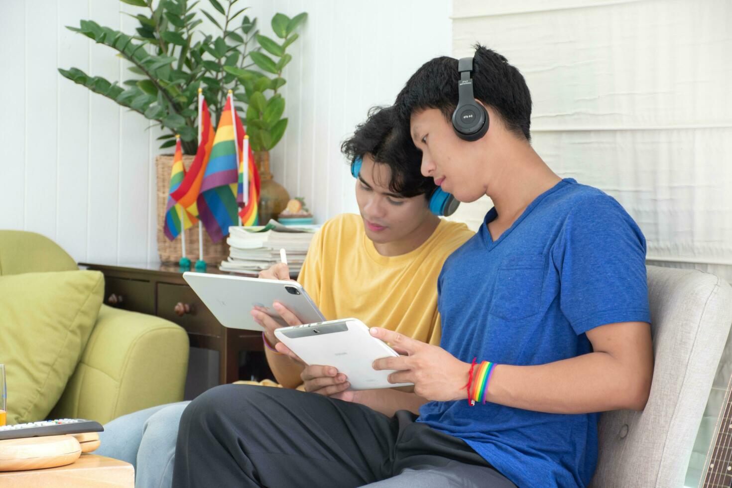 ritratto di Due giovane asiatico gay coppie seduta su divano, la spesa loro gratuito tempo e Guardando tv a casa insieme, concetto per stile di vita di lgbt persone in giro il mondo. foto