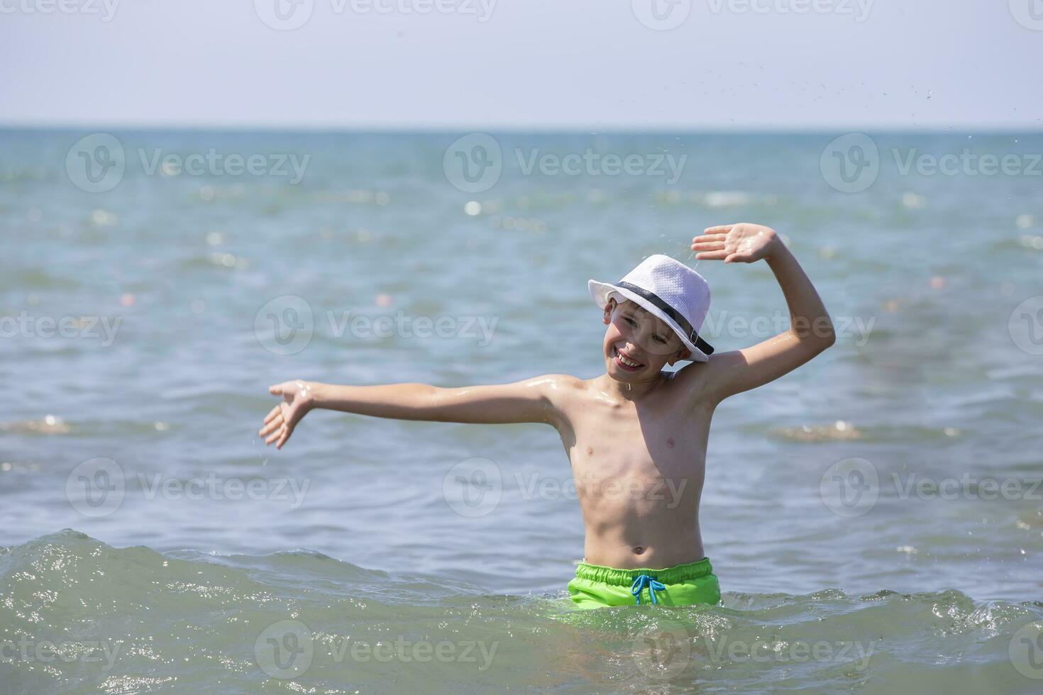 un' contento ragazzo nel un' bianca Panama nuotate nel il mare. foto