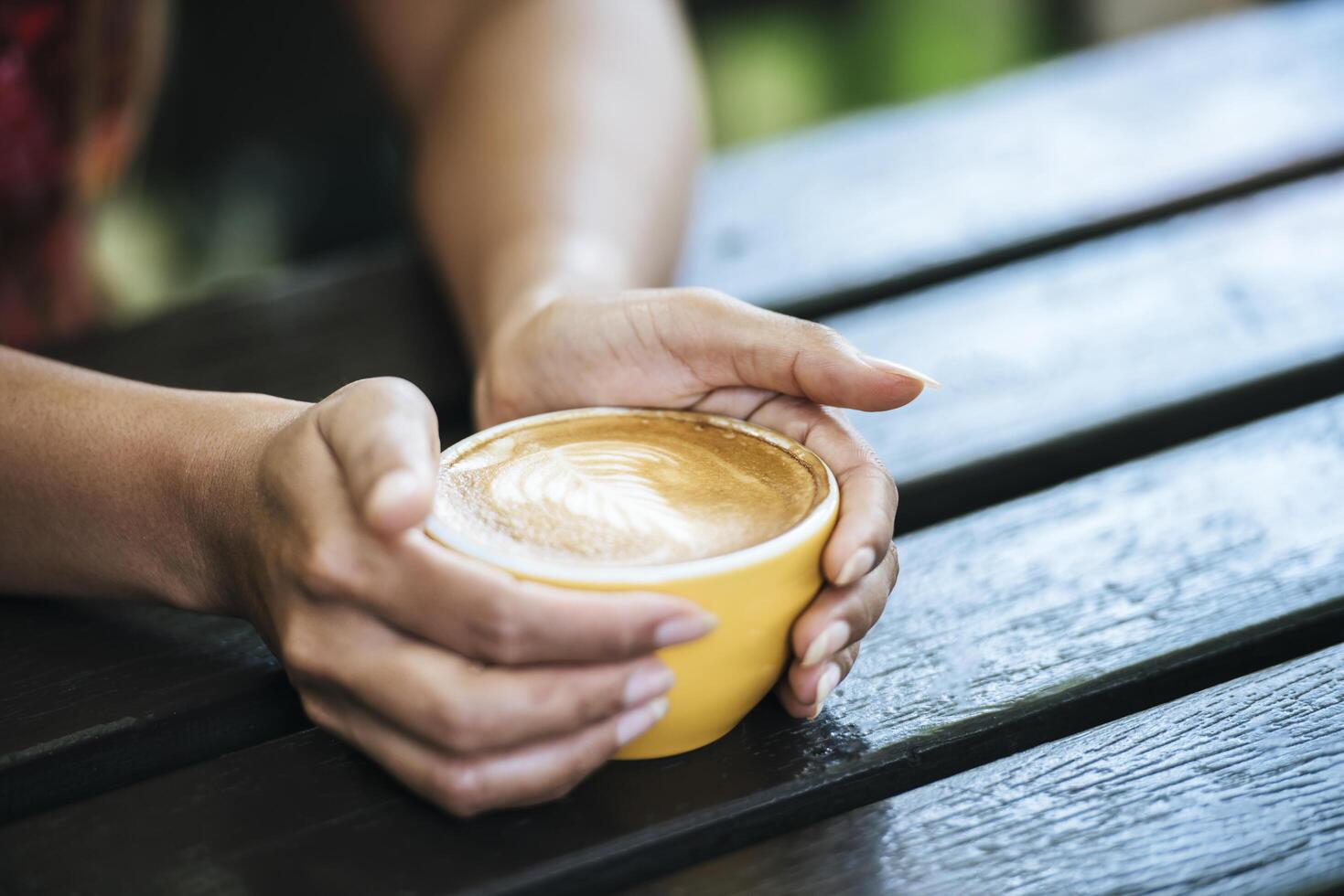 le mani della donna che tengono una tazza di caffè al bar foto