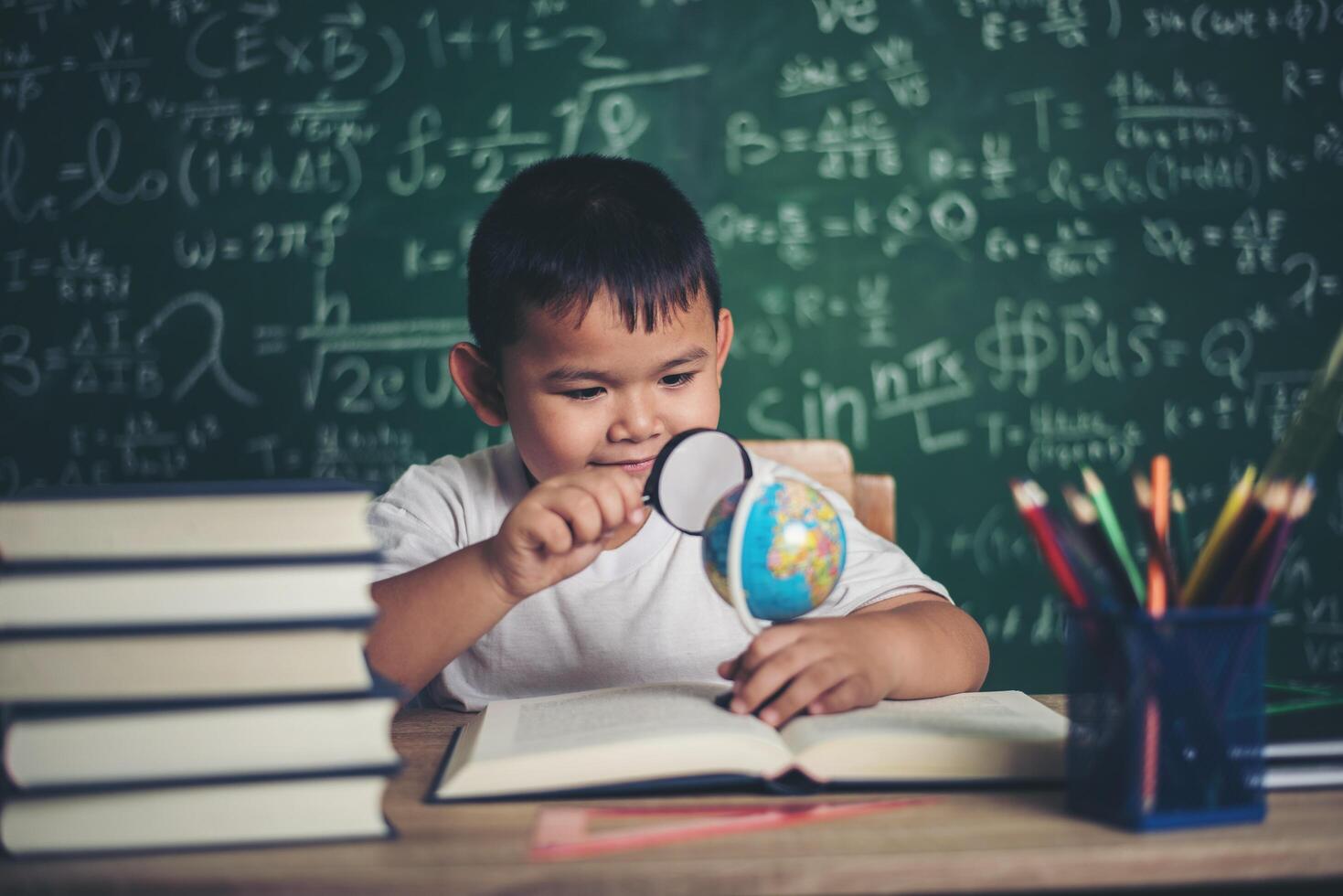 bambino che osserva o studia il modello educativo del globo in classe. foto