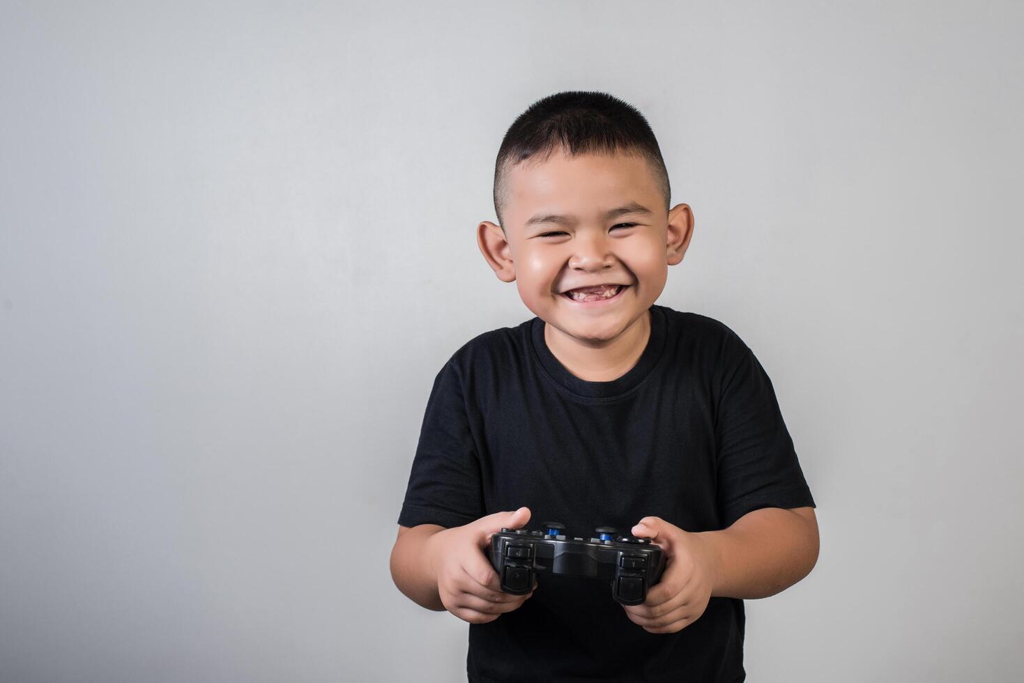 ragazzo felice gioca al computer con un controller in studio fotografico foto