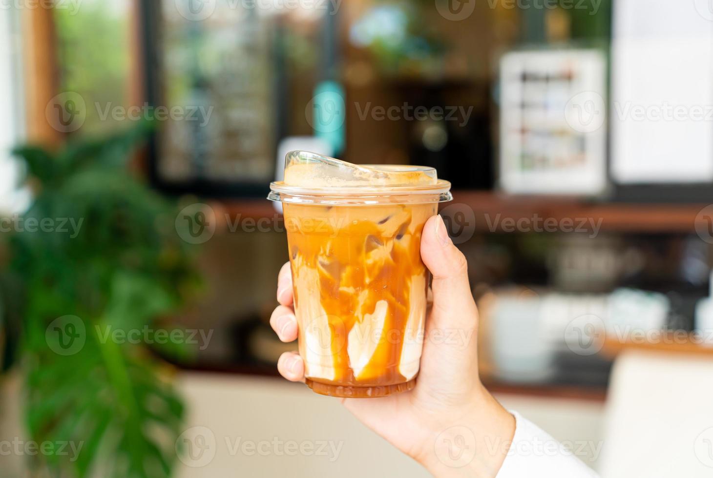 mano che tiene il bicchiere di caffè macchiato al caramello foto