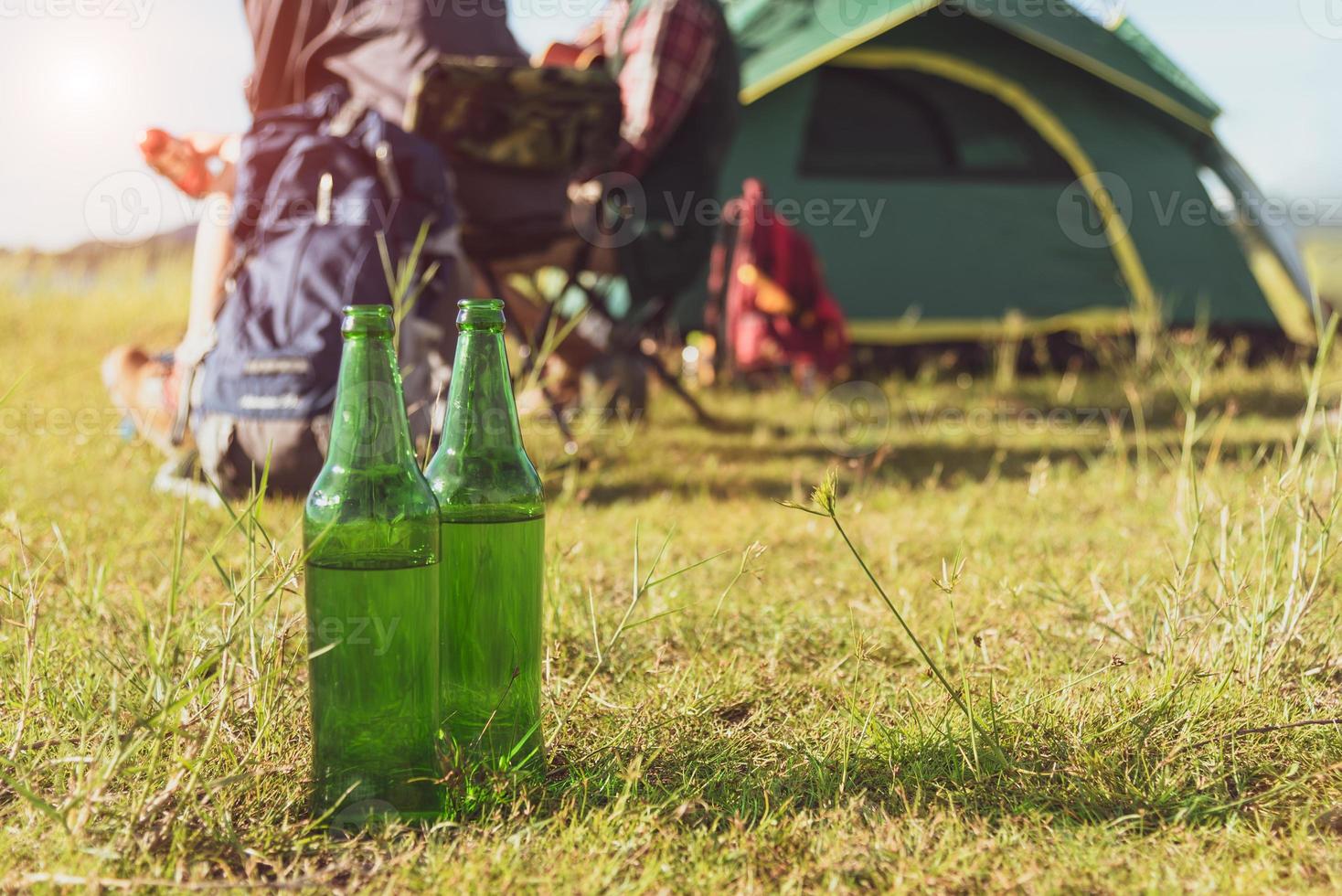 primo piano di una bottiglia di birra in un prato durante il campeggio all'aperto foto