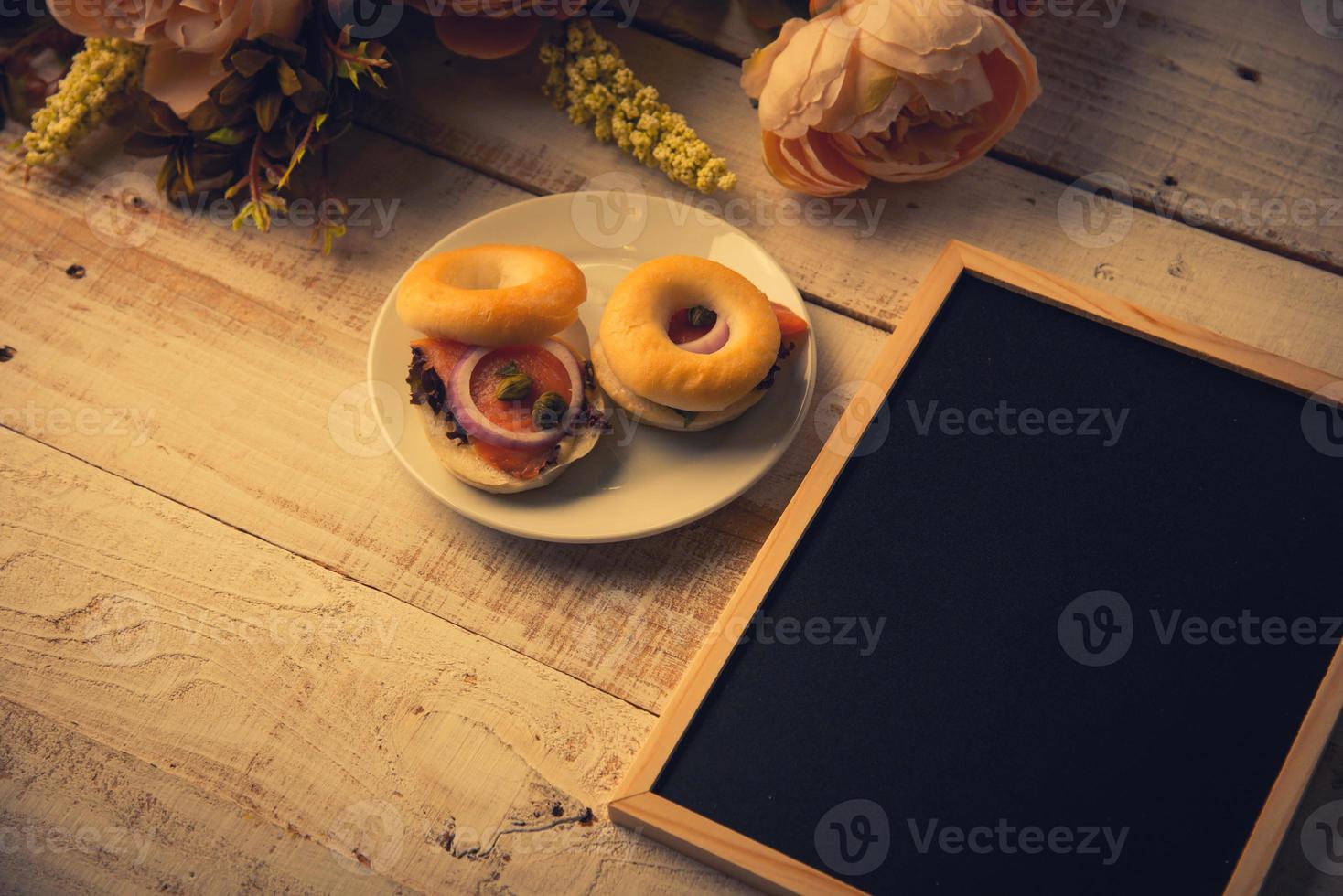 lavagna di legno vuota della scuola sul pavimento di legno con pane dell'hamburger foto