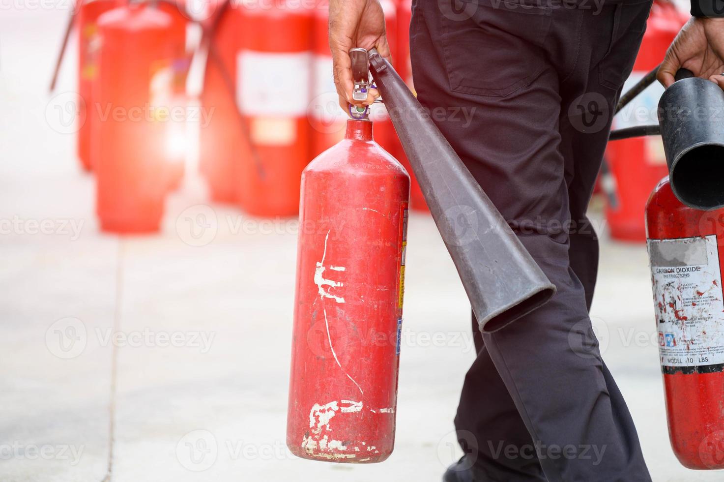 la parte inferiore del corpo del vigile del fuoco prepara l'esercitazione antincendio tenendo l'estintore portatile foto