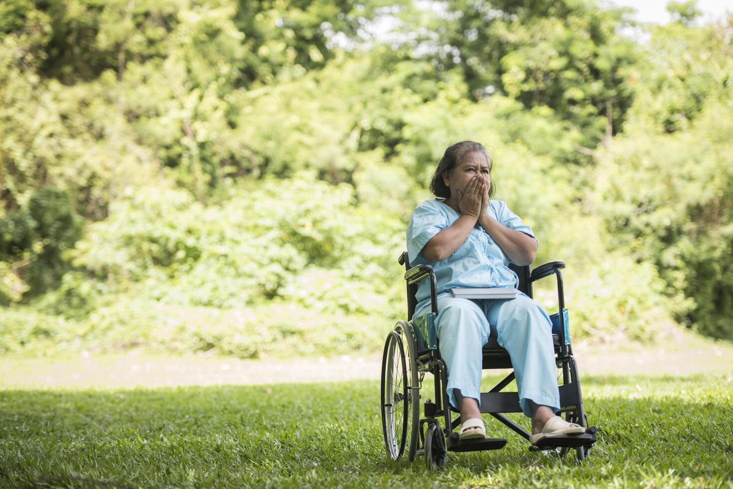 donna anziana solitaria seduta triste sensazione sulla sedia a rotelle in giardino foto