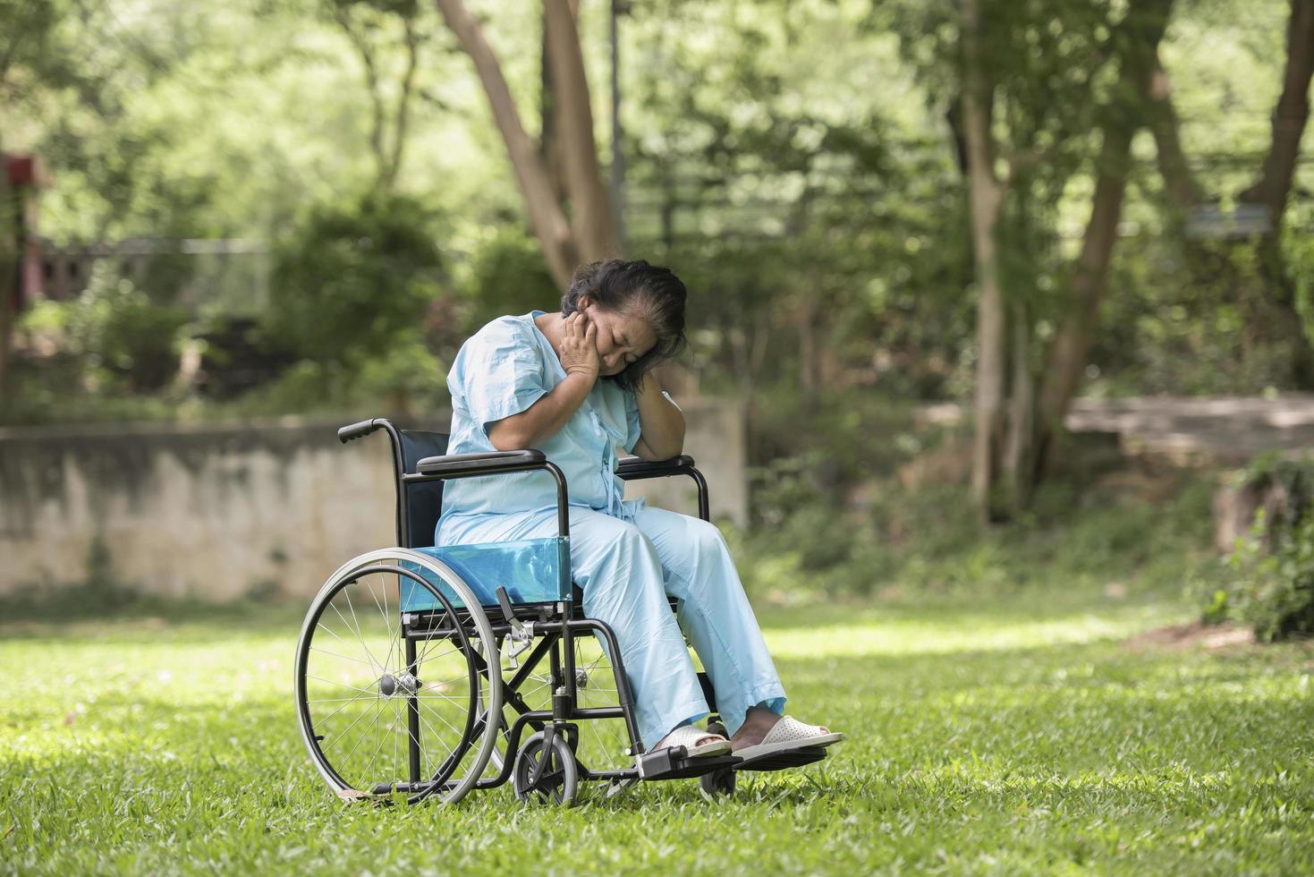 donna anziana solitaria seduta triste sensazione sulla sedia a rotelle in giardino foto