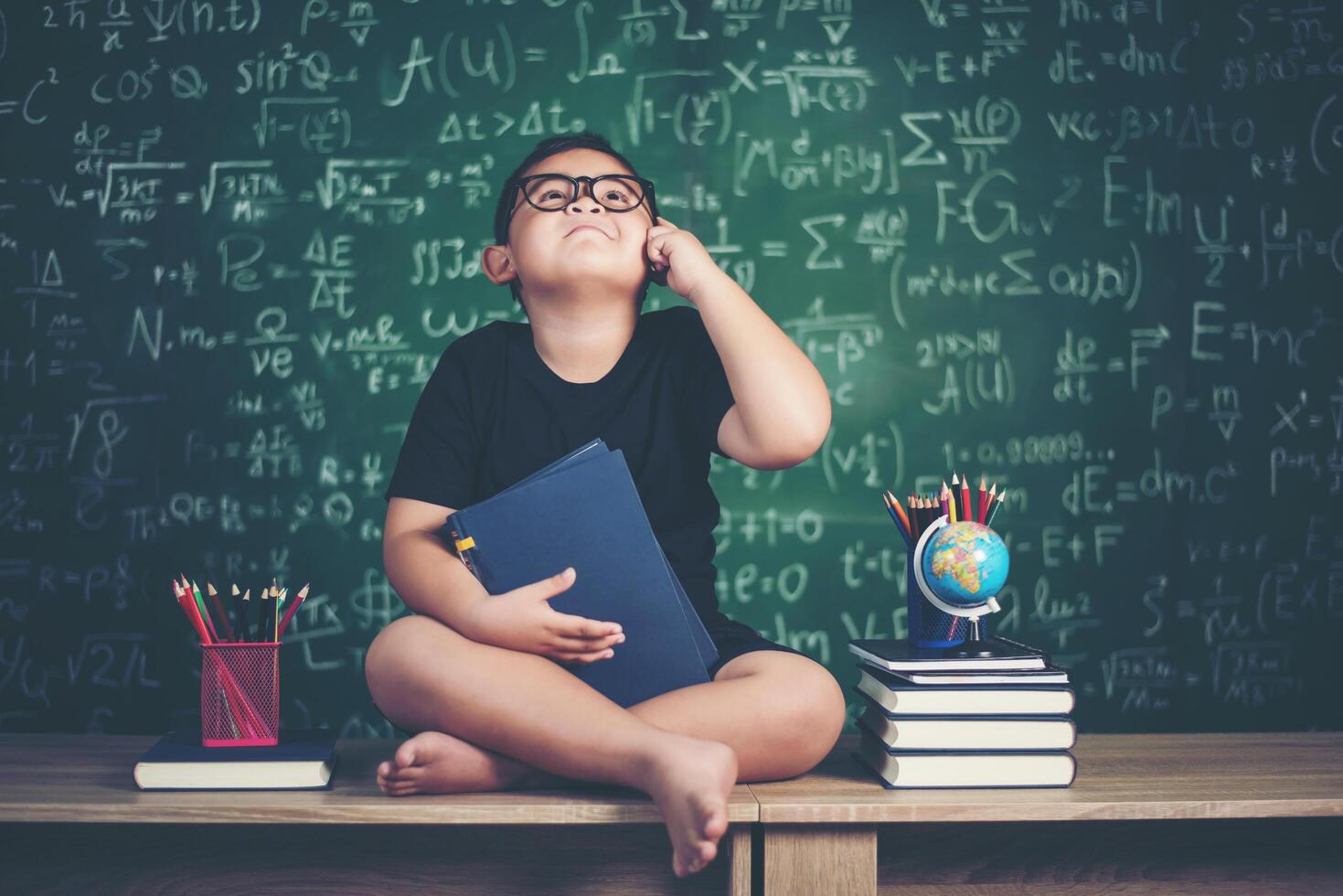 ragazzino premuroso con libro vicino a un consiglio scolastico foto