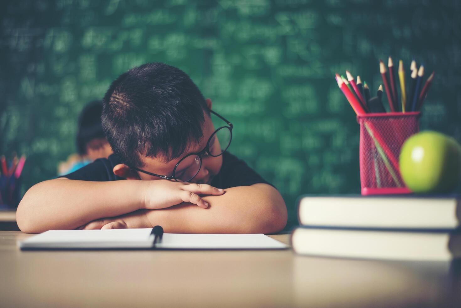 ragazzo che dorme sui libri in classe. foto