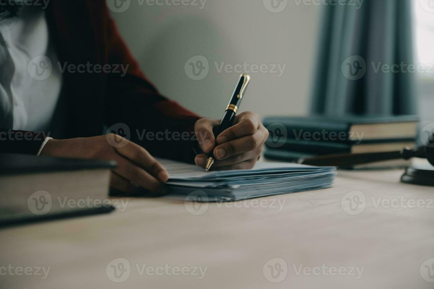 concetto di giustizia e diritto. giudice maschio in un'aula di tribunale con il martelletto, lavorando con computer e tastiera docking, occhiali, sul tavolo alla luce del mattino foto