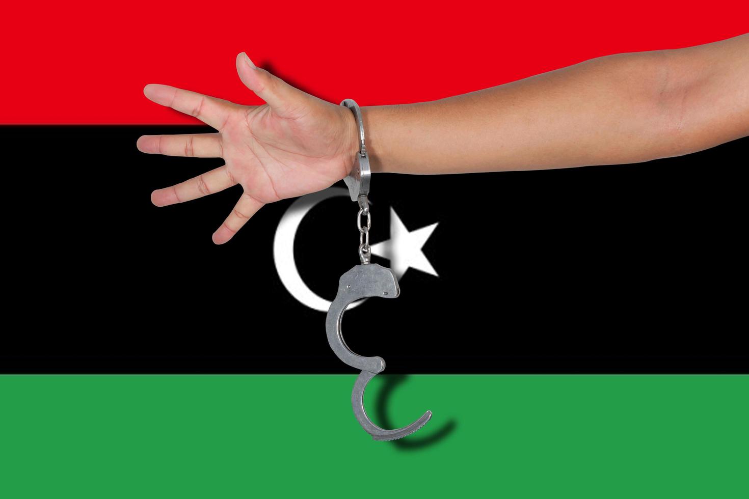 manette con mano sulla bandiera libia foto