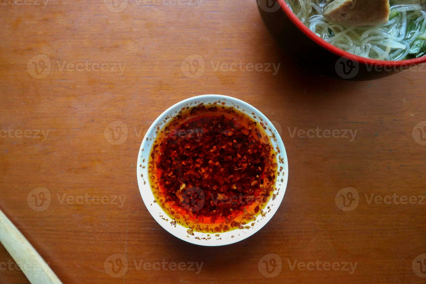 peperoncino olio. fatti in casa peperoncino olio nel un' bicchiere liite piatto, su tavolo foto