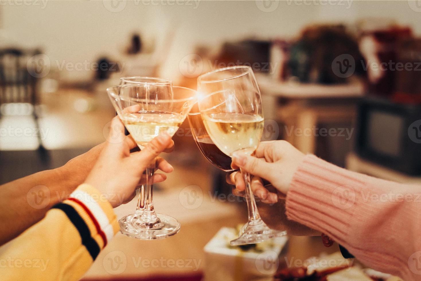 mani di persone che celebrano la festa di capodanno in casa con un bicchiere foto