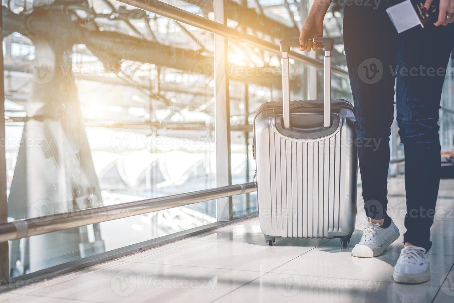 primo piano di una donna che viaggia e tiene in mano la valigia trolley in aeroporto foto